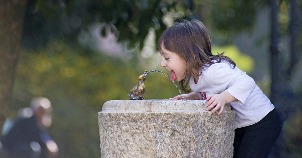 A girl preventing dehydration by sipping at a water fountain