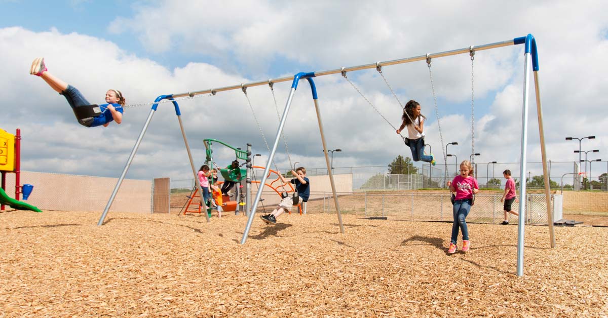 Children swinging on a commercial swing set